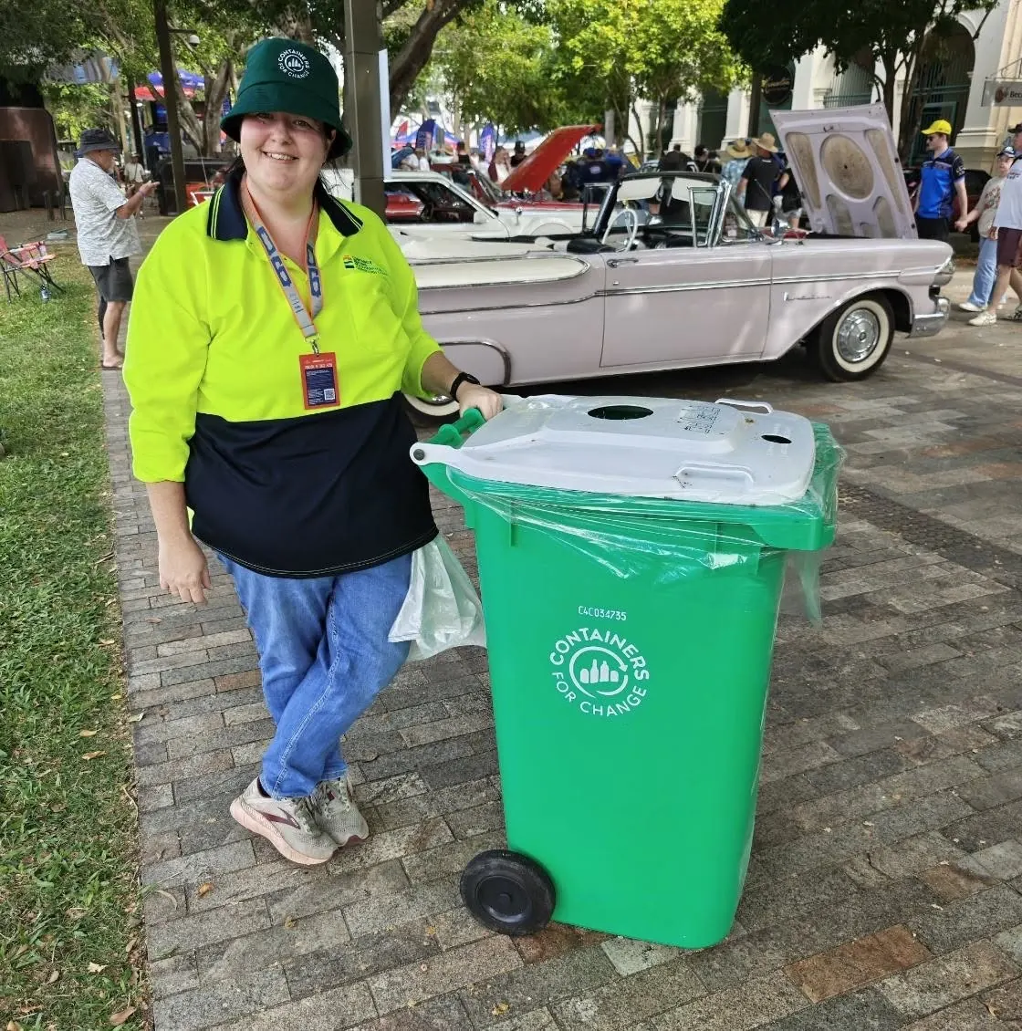 A Container Refund team member in hi-vis with a Containers for Change bin at a community event